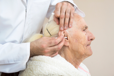 caregiver cleaning the ears of an senior woman using cotton swabs