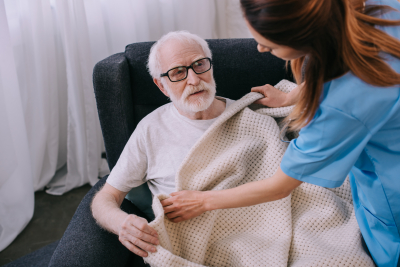 caregiver covering senior man with plaid