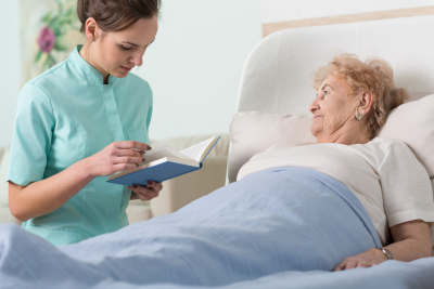 caregiver reading the booking while the ill senior woman listening